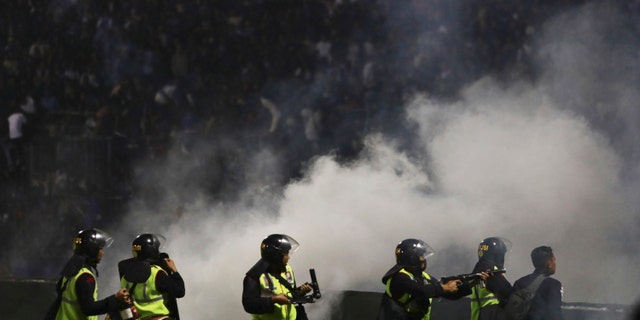 Police officers fire tear gas during a soccer match at Kanjuruhan Stadium in Malang, East Java, Indonesia, Saturday, Oct. 1, 2022.