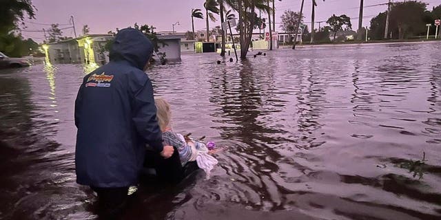 Johnny Lauder pushes his mother, Karen Lauder, 86, through floodwaters in a wheelchair after being rescued from her home, in Naples, Fla., Wednesday, Sept. 28, 2022, following Hurricane Ian.