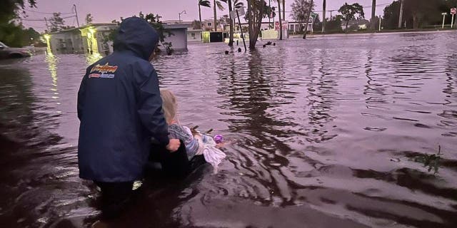 Johnny Lauder pushes his mother, Karen Lauder, 86, through floodwaters in a wheelchair after being rescued from her home, in Naples, Fla., Wednesday, Sept. 28, 2022, following Hurricane Ian.