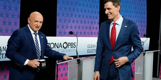 Arizona Democratic Sen. Mark Kelly, left, and his Republican challenger Blake Masters, right, arrive on stage prior to a televised debate in Phoenix, Thursday, Oct. 6, 2022. 