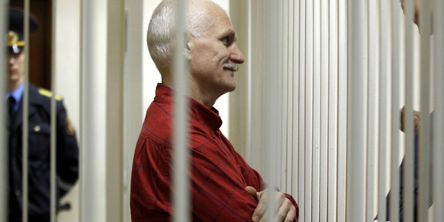 Ales Belyatsky, the jailed leader of Vesna, the most important human rights group in Belarus, greets his relatives as he sits in a cage during a court session in Minsk, Belarus on Thursday, November 24, 2011. 