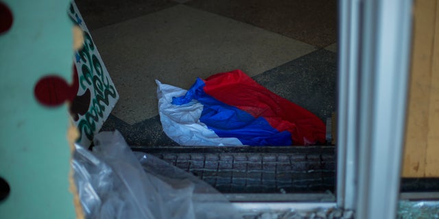 A Russian flag lies on the ground of a partially damaged culture centre in the recently retaken village of Borova village, east Ukraine, Friday, Oct. 7, 2022.