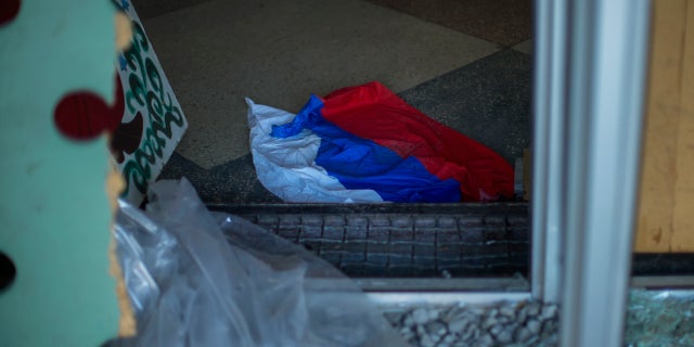 A Russian flag lies on the ground of a partially damaged culture centre in the recently retaken village of Borova village, east Ukraine, Friday, Oct. 7, 2022.