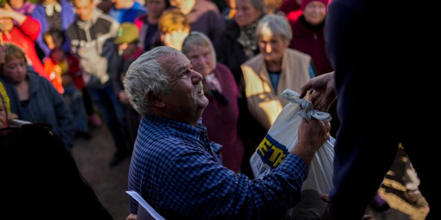 Locals receive food given by Ukrainian volunteers in the recently retaken village of Boguslavka village, east Ukraine, Friday, Oct. 7, 2022.