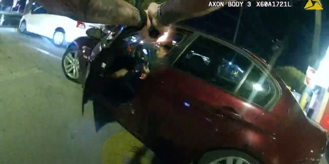 In this image taken from Oct. 2, 2022 police body camera video and released by San Antonio Police Department, San Antonio Police officer James Brennand shoots Erik Cantu, who was holding a hamburger in a fast food restaurant parking lot, as Cantu drives away in San Antonio, Texas.