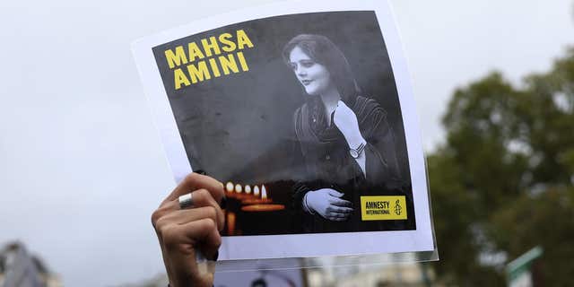A protester shows a portrait of Mahsa Amini during a rally to support Iranian protesters who oppose their leadership over the death of a young woman in police custody, Sunday October 2, 2022 in Paris. 
