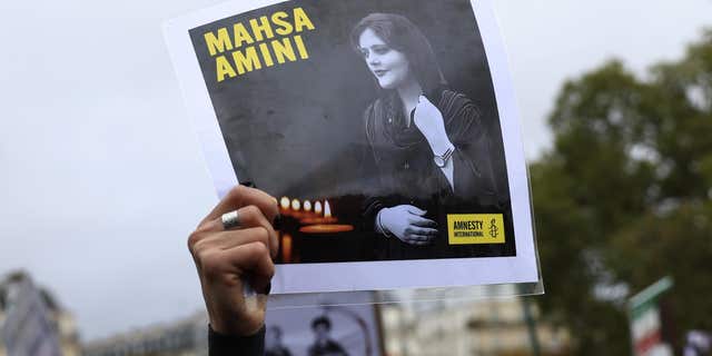 A protester shows a portrait of Mahsa Amini during a rally to support Iranian protesters who oppose their leadership over the death of a young woman in police custody, Sunday October 2, 2022 in Paris. 