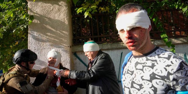 People receive medical treatment at the scene of Russian shelling, in Kyiv, Ukraine, Oct. 10, 2022. Multiple explosions rocked Kyiv early Monday following months of relative calm in the Ukrainian capital. Kyiv Mayor Vitali Klitschko reported explosions in the city's Shevchenko district, a large area in the center of Kyiv that includes the historic old town as well as several government offices. 