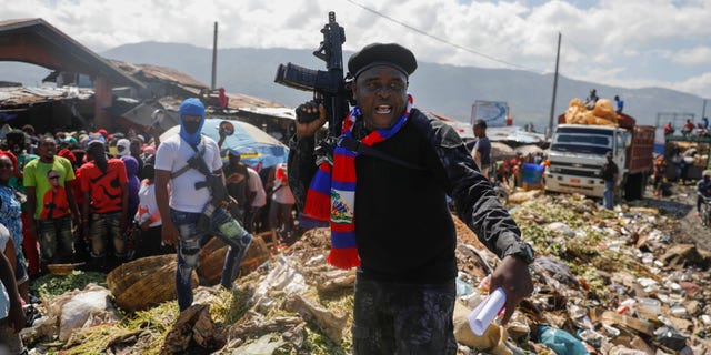 Barbecue, the leader of the "G9 and Family" gang, stands next to garbage in the La Saline neighborhood in Port-au-Prince, Haiti, Friday, Oct. 22, 2021. 