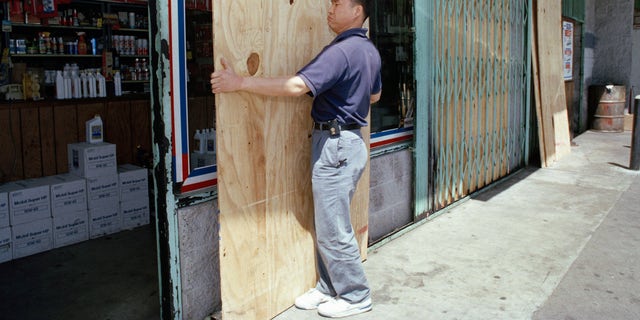 FILE - Chae Son Han, who works in an auto parts store in Los Angeles' Koreatown, takes down protective boards outside his store on April 19, 1993. Business was almost back to normal after verdicts in the Rodney King civil rights trail. (AP Photo/Nick Ut, File)