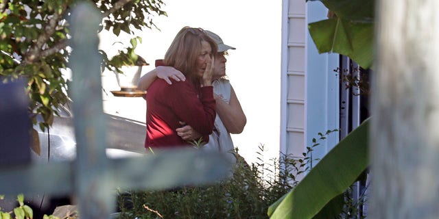 Neighbors embrace as police remain on the scene at Castle Pines Dr. and Sahalee Way following a shooting Thursday night in Raleigh, N.C.,  on Friday, Oct. 14, 2022. Police say a 15-year-old boy fatally shot at least two people in the streets of a neighborhood in North Carolina’s capital city, then fled toward a walking trail, where he opened fire, killing and wounding others.