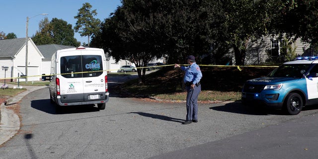 A Raleigh police officer allows a person to return home on Sahalee Way, which remains closed except for residents following a shooting in Raleigh, N.C., seen on Friday, Oct. 14, 2022. 