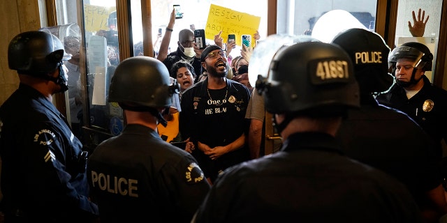 Protesters chant a slogan as they face off with police at the entrance of the Los Angeles City Hall in Los Angeles, Tuesday, Oct. 18, 2022.