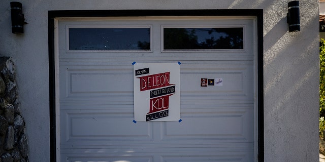 A sign demanding a resignation from LA City Councilmember Kevin de Leon is posted on the garage door of his home in Los Angeles, Tuesday, Oct. 18, 2022.