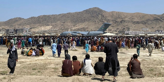 Hundreds of people gather near a U.S. Air Force C-17 transport plane at the perimeter of the international airport in Kabul, Afghanistan, Aug. 16, 2021. 