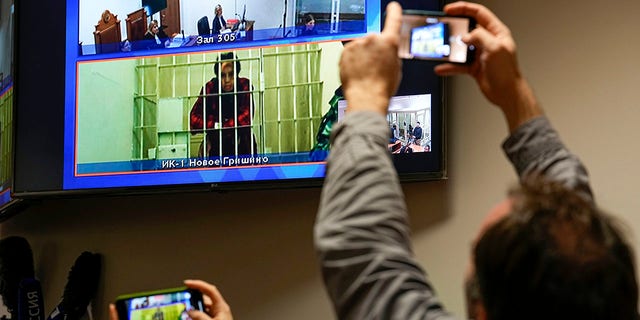 WNBA star and two-time Olympic gold medalist Brittney Griner is seen on the bottom part of a TV screen as she waits to appear in a video link provided by the Russian Federal Penitentiary Service prior to a hearing at the Moscow Regional Court in Moscow, Russia, on Oct. 25, 2022.