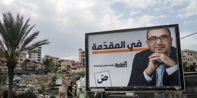 A man walks by an election campaign billboard showing Sami Abu Shehadeh, head of the nationalist Balad party, in the northern Israeli city of Umm al-Fahm, Oct. 21, 2022.  