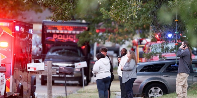People look on as Broken Arrow, Okla., police and fire department investigate the scene of a fire with multiple fatalities.
