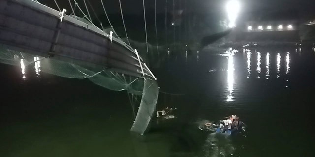 Redders op boten zoeken in de Machchu-rivier naast een kabelbrug die instortte in het Morbi-district, in de westelijke staat Gujarat, India, zondag 30 oktober 2022. 