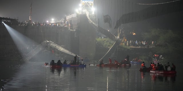 Rescuers on boats search in the Machchu river next to a cable suspension bridge that collapsed in Morbi town of western state Gujarat, India, Monday, Oct. 31, 2022.