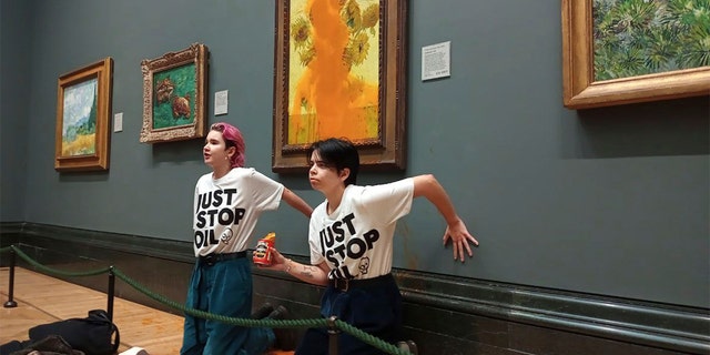 Two protestors kneel after throwing juice on Vincent van Gogh's famous 1888 work "It's sunny" at the National Gallery in London, October.  14, 2022.