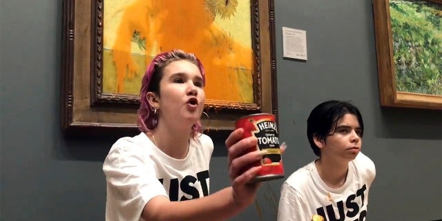 Handout photo issued by Just Stop Oil of two protesters who have thrown tinned soup at Vincent Van Gogh's famous 1888 work Sunflowers at the National Gallery in London, Friday Oct. 14, 2022. 