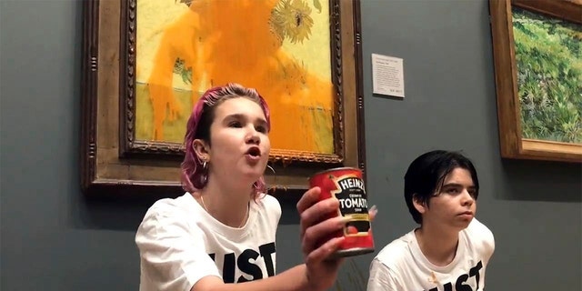 Handout photo issued by Just Stop Oil of two protesters who have thrown tinned soup at Vincent Van Gogh's famous 1888 work Sunflowers at the National Gallery in London, Friday Oct. 14, 2022. 