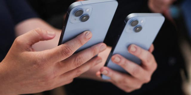 Un ospite tiene in mano un nuovo iPhone 14 a un evento Apple presso la sede centrale di Cupertino, in California, il 7 settembre 2022.  
