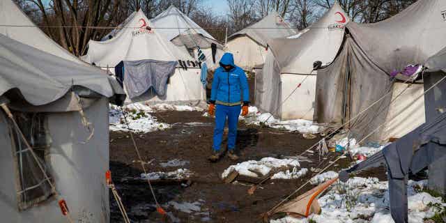A migrant walks between tents at the Vucjak refugee camp outside Bihac, northwestern Bosnia, on Dec. 6, 2019. Germany met with the European Union on Oct. 19, 2022, to discuss curbing migration on the Balkan route.