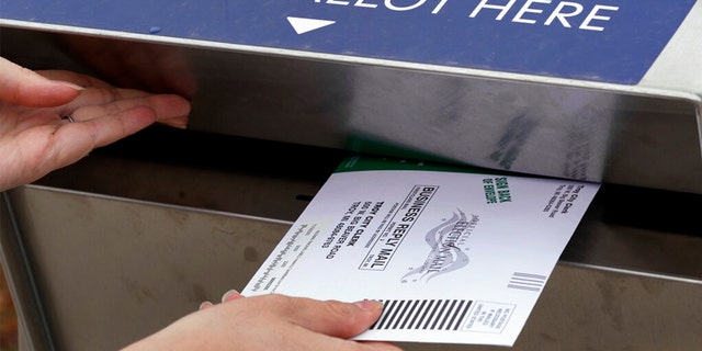 A Michigan voter inserts her absentee voter ballot into a drop box in Troy, Mich on Oct. 15, 2020.