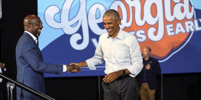 Former President Barack Obama, right, is greeted by U.S. Sen. Raphael Warnock, candidate for U.S. Senate, as he steps on stage to speak at a campaign rally, Friday, Oct. 28, 2022, in College Park, Ga. (AP Photo/John Bazemore)