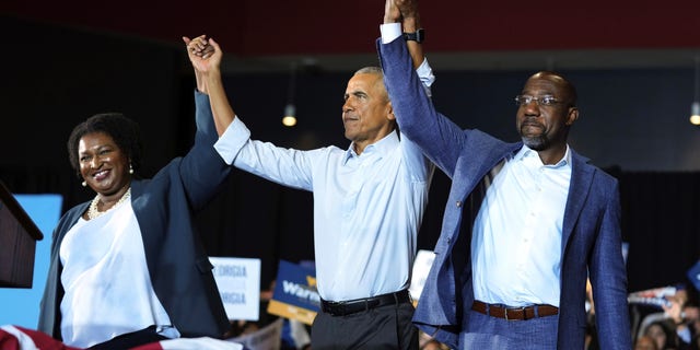 Former President Obama, center, stands with Georgia gubernatorial candidate Stacey Abrams and U.S. Senate candidate Sen. Raphael Warnock, D-Ga., during a campaign rally on Friday, 28 October 2022 in College Park, Georgia.