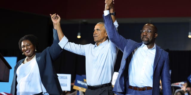 Former President Obama, center, stands with Georgia gubernatorial candidate Stacey Abrams and candidate for U.S. Senate, Sen. Raphael Warnock D-Ga., during a campaign rally Friday, Oct. 28, 2022, in College Park, Georgia.