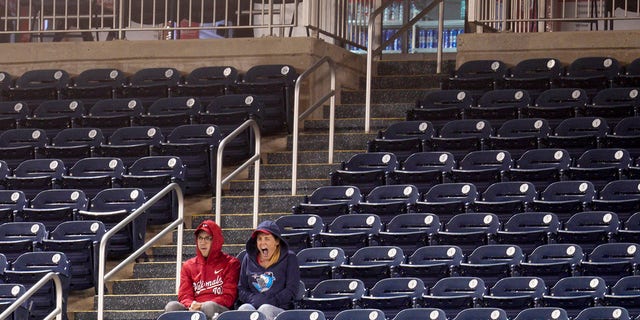 Two Washington Nationals fans watch a game against the Atlanta Braves surrounded by empty seats during the ninth inning at Nationals Park Sept. 27, 2022, in Washington, D.C.