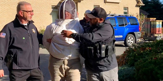 Rorie S. Woods, 55, of Hadley, Mass., center, wears a beekeeping suit while being taken into custody by Hampden County Sheriff's Department officers, in Longmeadow, Mass. Woods is accused of unleashing bees on sheriff's deputies serving an eviction notice, one of many bizarre crimes in 2022.