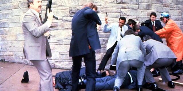 James Brady and a police officer are seen lying on the ground after being shot while the suspect John Hinckley Jr. is apprehended, at right, moments after the attempted March 30, 1981, assassination of President Ronald Reagan in Washington, D.C.