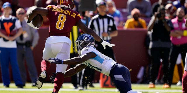 Washington Commanders running back Brian Robinson Jr., left, rushes past Tennessee Titans cornerback Roger McCreary in the first half of an NFL football game, Sunday, Oct. 9, 2022, in Landover, Md. 