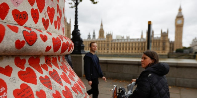 People walk by the National Covid Memorial Wall, a dedication of thousands of hand painted hearts and messages commemorating victims of the COVID-19 pandemic, in London, Britain, October 4, 2022. 