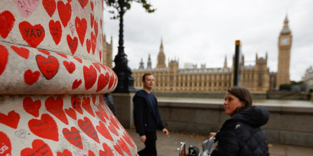 People walk by the National Covid Memorial Wall, a dedication of thousands of hand painted hearts and messages commemorating victims of the COVID-19 pandemic, in London, Britain, October 4, 2022. 