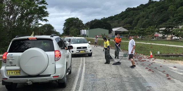 In this handout image provided by Parks Australia, members of the public and Parks Australia staff rack away thousands of red crabs off a road on November 23, 2021, in Christmas Island.