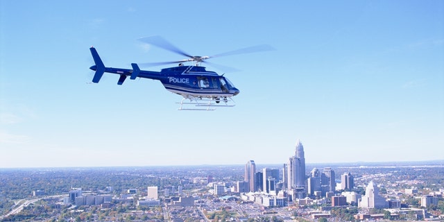 A police helicopter flies over Charlotte, North Carolina. Authorities said a helicopter crashed near a freeway on Tuesday, killing two people. Officials have not confirmed who owns the helicopter.