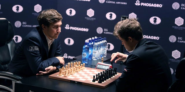 Sergey Karjakin of Russia, left, and current World Chess Champion Magnus Carlsen of Norway prepare for the start of the first game of their rapid chess match playoff at the 2016 World Chess Championship match in New York Nov. 30, 2016.