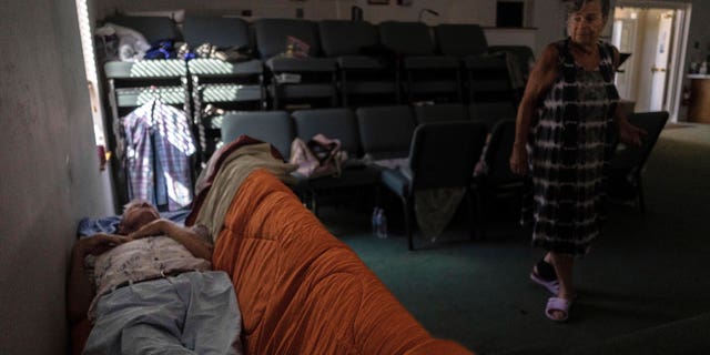 A man sleeps inside the sanctuary of the Southwest Baptist Church in Fort Myers, Fla., on Sunday, Oct. 2, 2022. The church has become a shelter for more than a dozen parishioners after Hurricane Ian devastated the region. (AP Photo/Robert Bumsted)