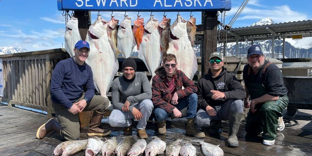 Captain John Moline, right, poses for a photo with others during the annual ASYMCA Alaska Combat Fishing Tournament on May 25, 2022, in Seward, Alaska. The tournament, which began in 2007 and now involves more than 300 soldiers, includes a day of deep-water fishing followed by a celebratory banquet with prizes for the largest catch, smallest catch and soldier who got the sickest.