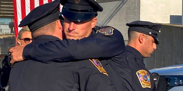 Two Bristol police officers embrace before a joint police funeral, Friday, Oct. 21, 2022, in East Hartford, Conn.