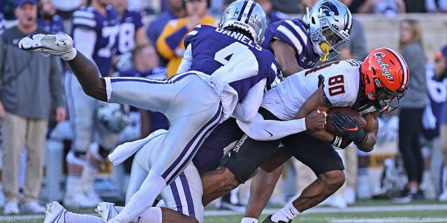 MANHATTAN, KS - OCTOBER 29:  Cornerback Omar Daniels #4 and safety Josh Hayes #1 of the Kansas State Wildcats tackle wide receiver Brennan Presley #80 of the Oklahoma State Cowboys during the second half at Bill Snyder Family Football Stadium on October 29, 2022 in Manhattan, Kansas.