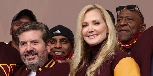 Team co-owners Dan and Tanya Snyder pose for a photo with former team members during the announcement of the Washington Football Team's name change to the Washington Commanders at FedEx Field Feb. 2, 2022, in Landover, Md.