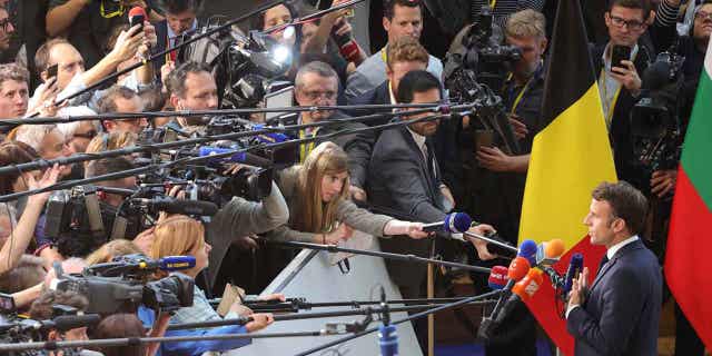 France's President Emmanuel Macron speaks with the media as he arrives for an EU summit at the EU Council building in Brussels, on Oct. 20, 2022. European Union leaders are heading into a two-day summit with opposing views on whether the bloc could impose a gas price cap to contain the energy crisis.