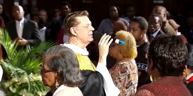 Father Michael Pfleger performing a sermon. 