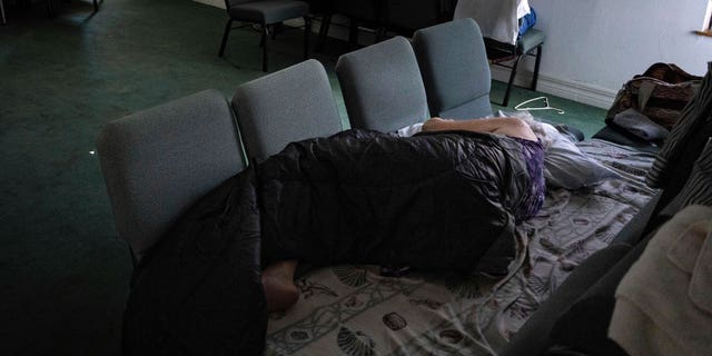 A woman sleeps in a chair bed inside the sanctuary of Southwest Baptist Church in Fort Myers, Florida, Sunday, October 2, 2022. Nearly a dozen parishioners live within the church after her home was destroyed by Hurricane Ian.  (AP Photo/Robert Bumsted)